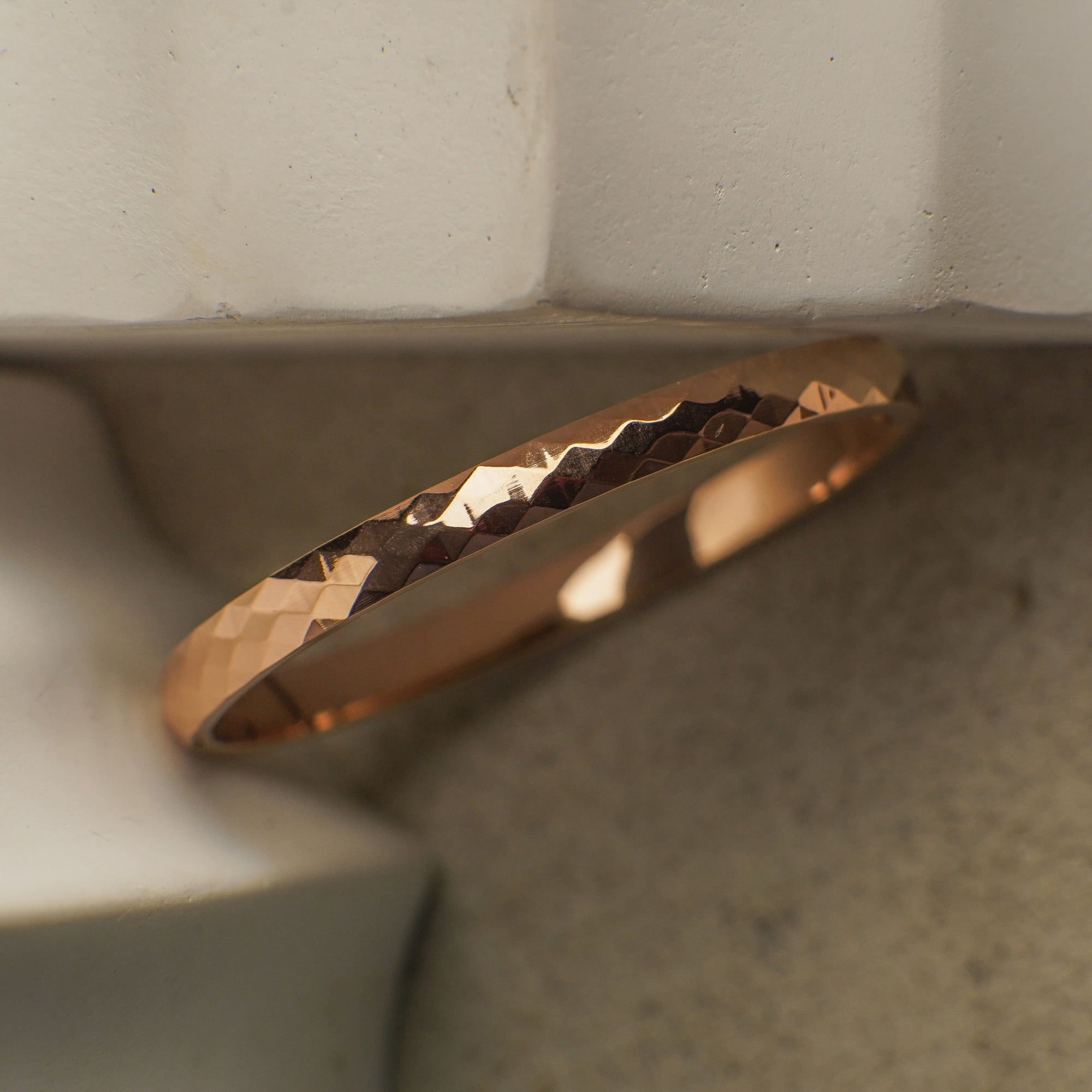 Gold ring with a textured design on a neutral background