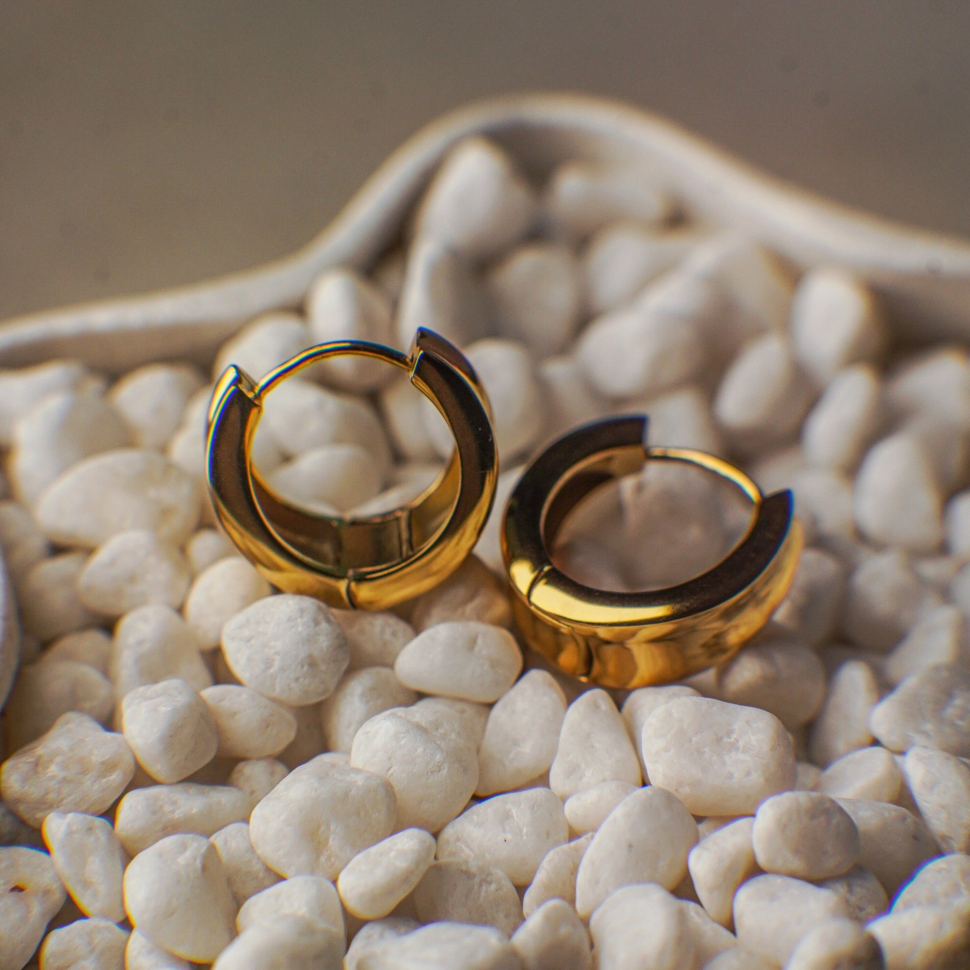 Gold hoop earrings on a bed of small white stones