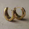 Pair of gold hoop earrings on a textured surface