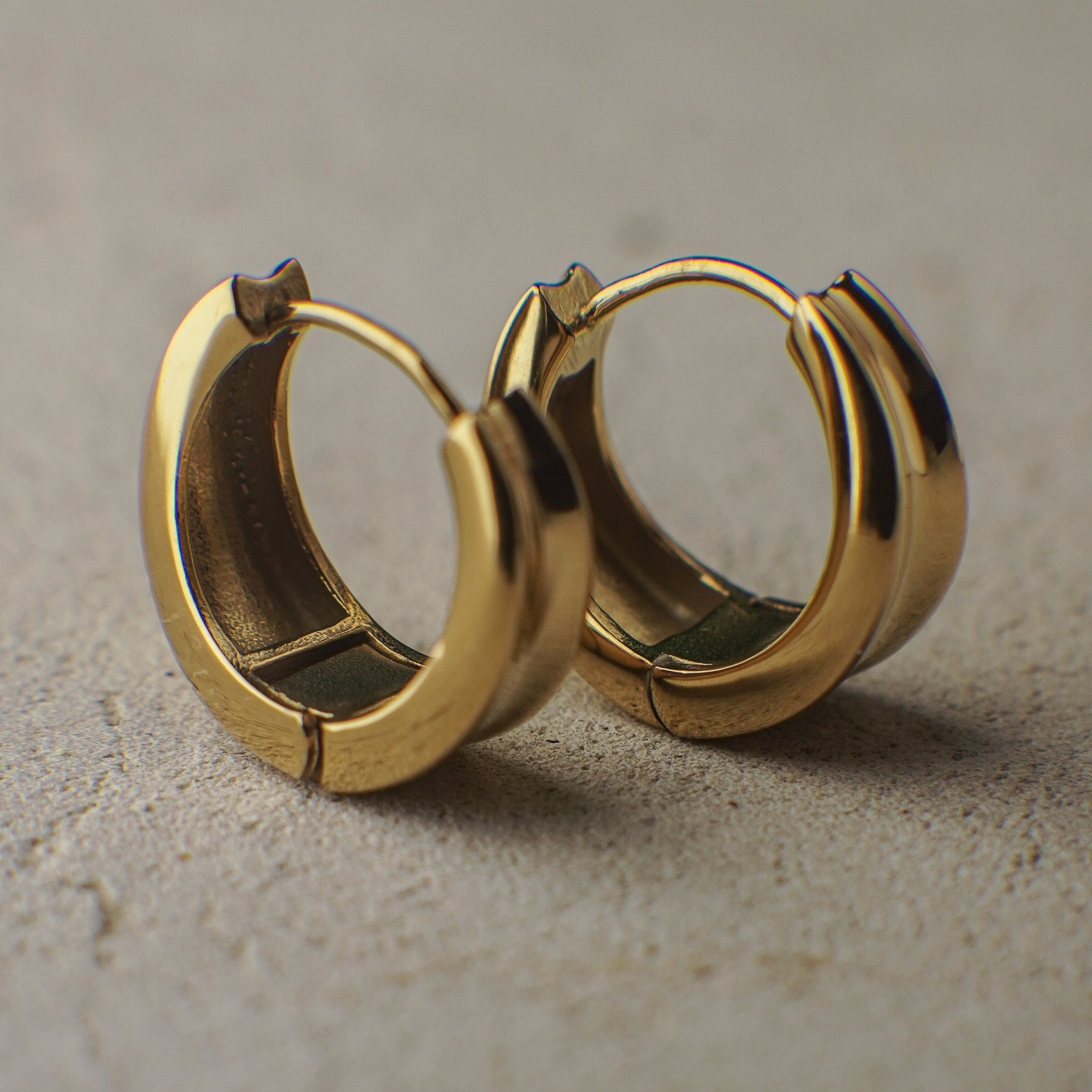 Pair of gold hoop earrings on a textured surface