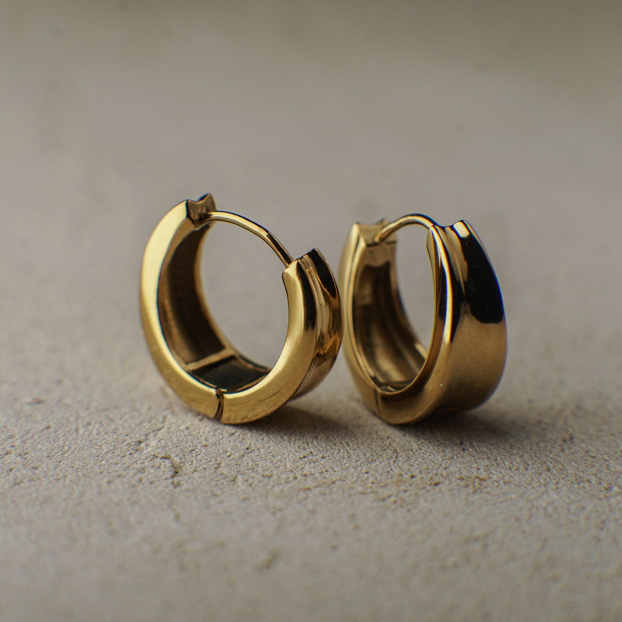 Gold hoop earrings on a beige surface