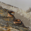 Gold hoop earrings on a textured stone surface