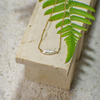 Gold necklace with a pendant on a stone surface with a green leaf