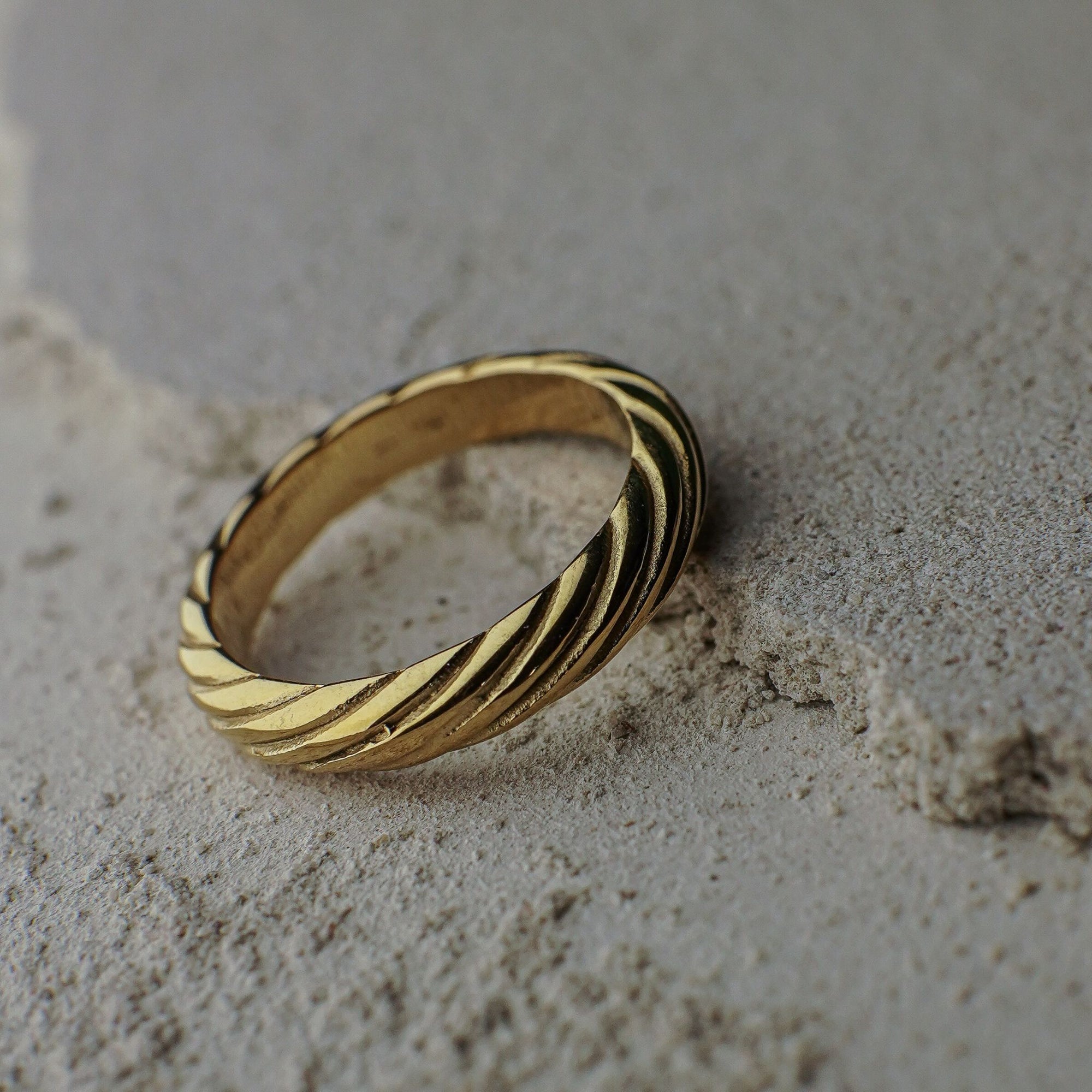 Gold ring with a zebra pattern on a sandy surface