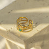 Gold ring with a green gemstone on a textured stone surface
