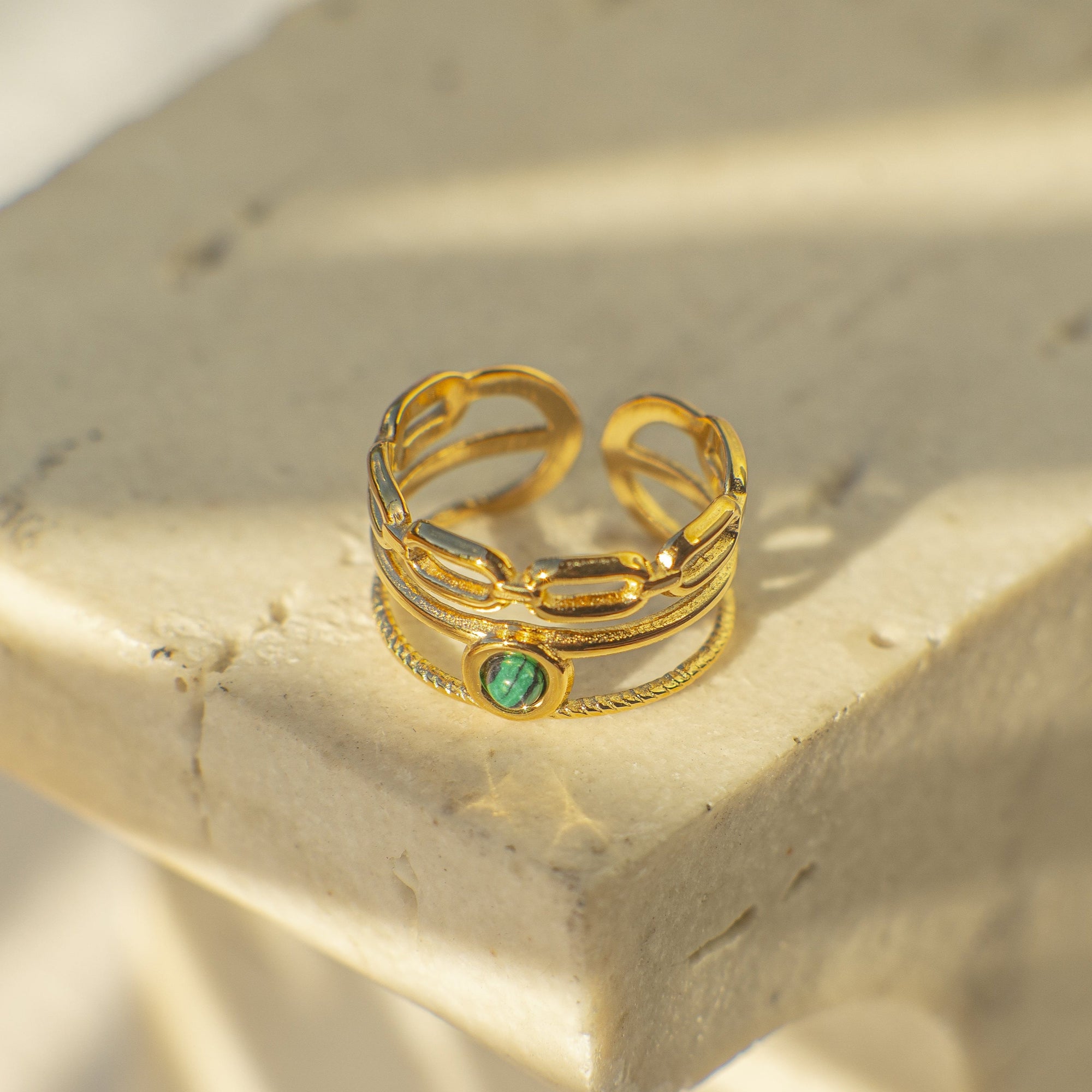 Gold ring with a green gemstone on a textured surface