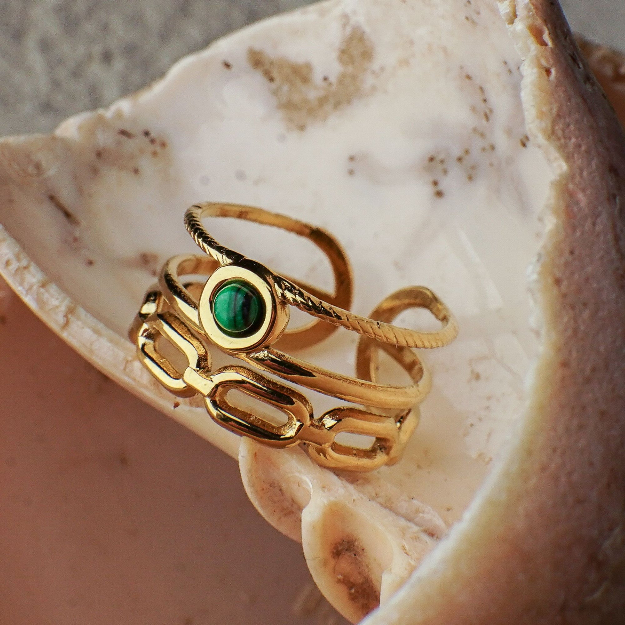 Gold ring with a green gemstone on a seashell