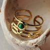 Gold ring with a green gemstone on a shell background