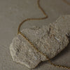 Gold chain necklace on a textured stone surface