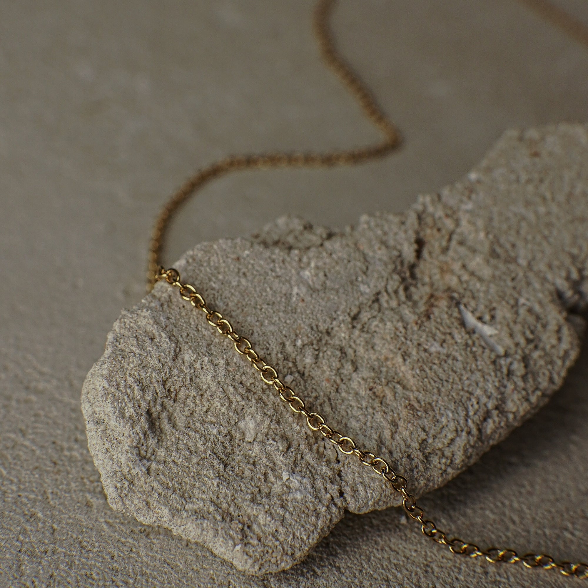 Gold chain necklace on a textured stone surface