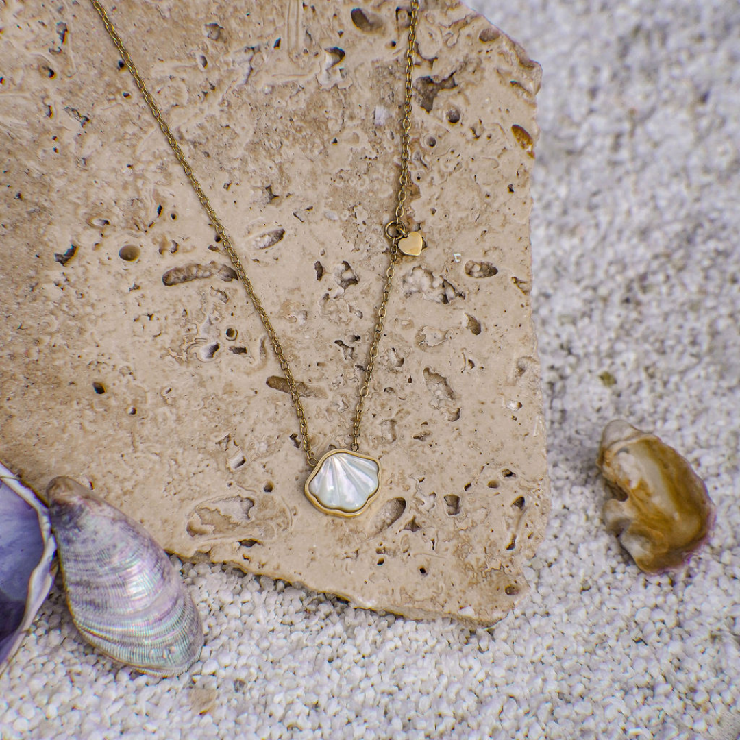 Necklace with a pendant on a sandy surface with shells