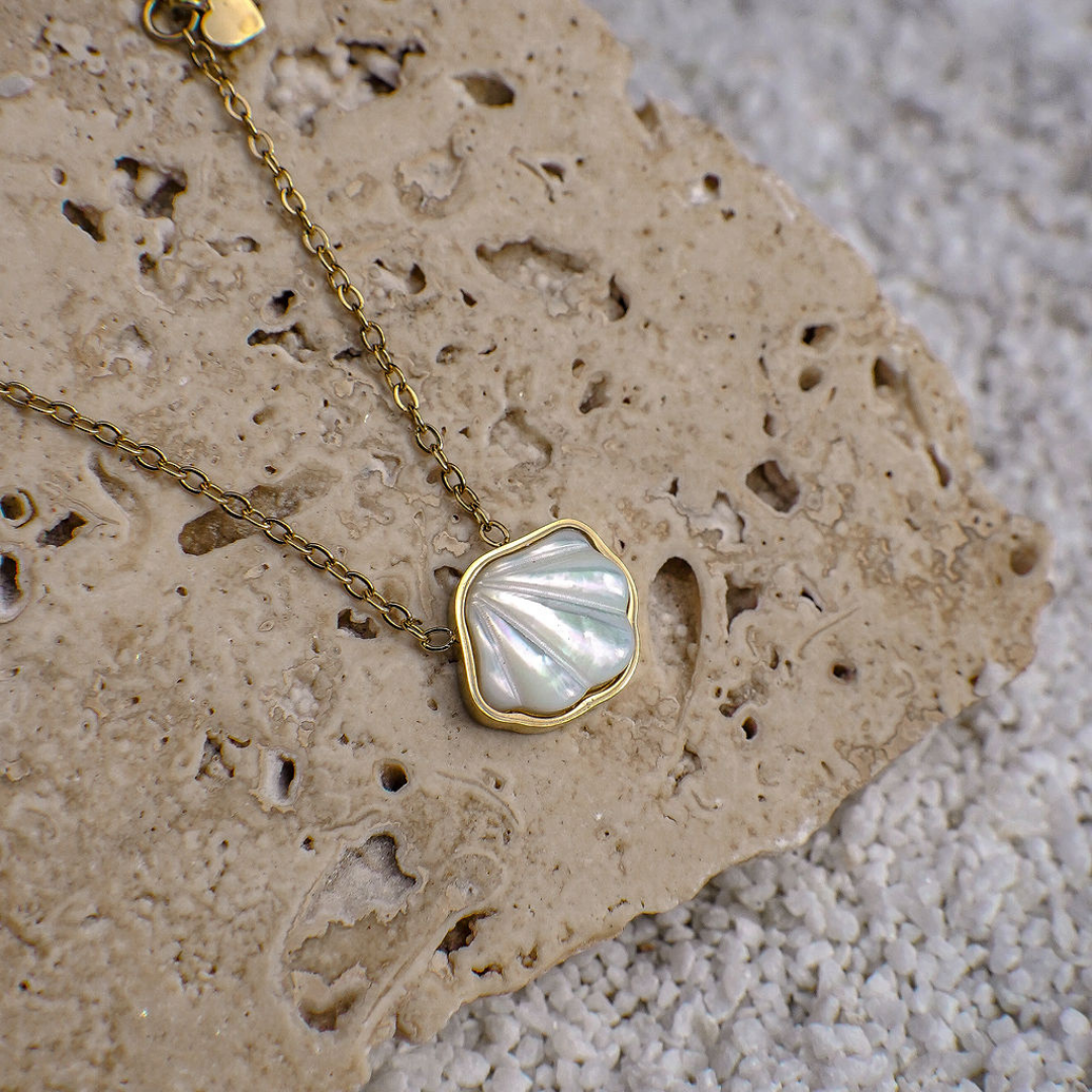 Necklace with a shell pendant on a textured stone surface