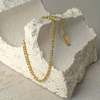 Gold chain necklace on a textured stone surface