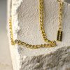 Gold chain necklace on a textured stone surface