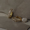 Gold hoop earrings with diamond accents on a textured surface