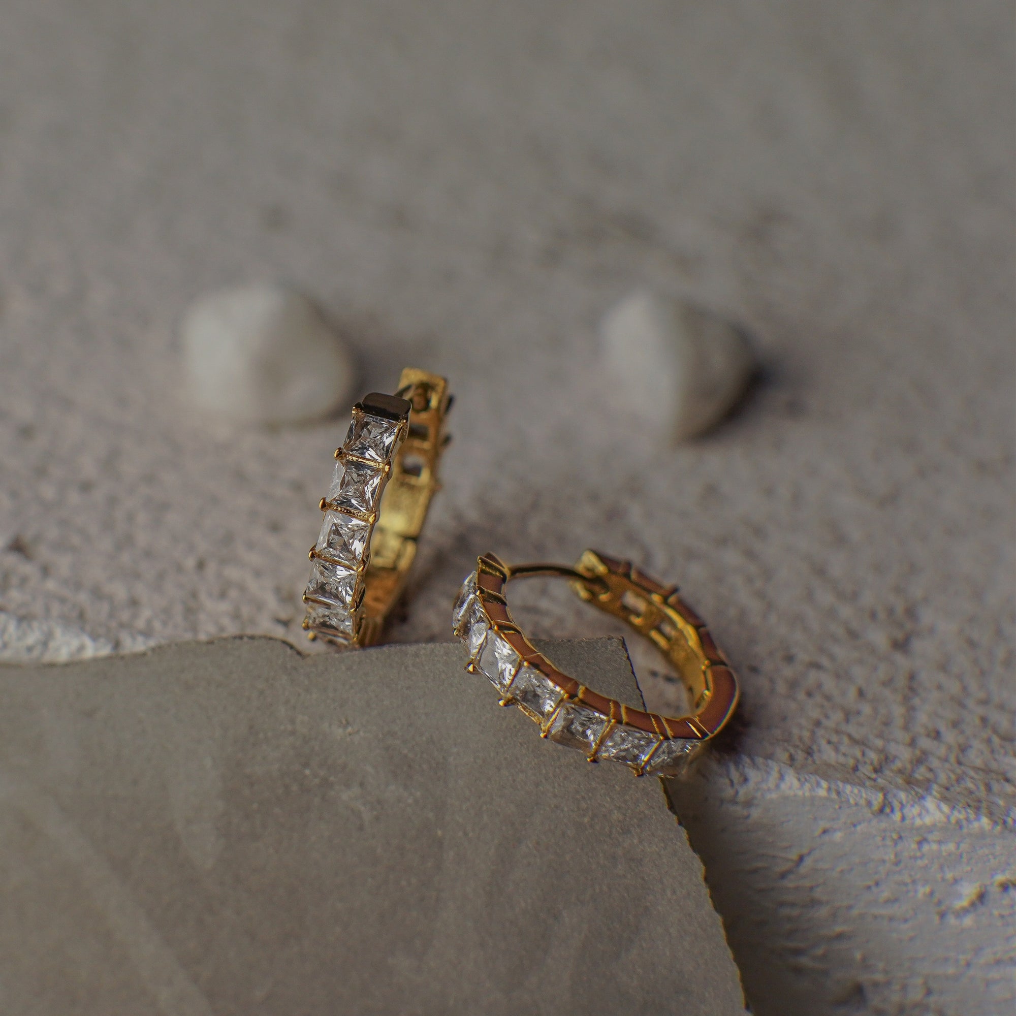 Gold hoop earrings with diamond accents on a textured surface