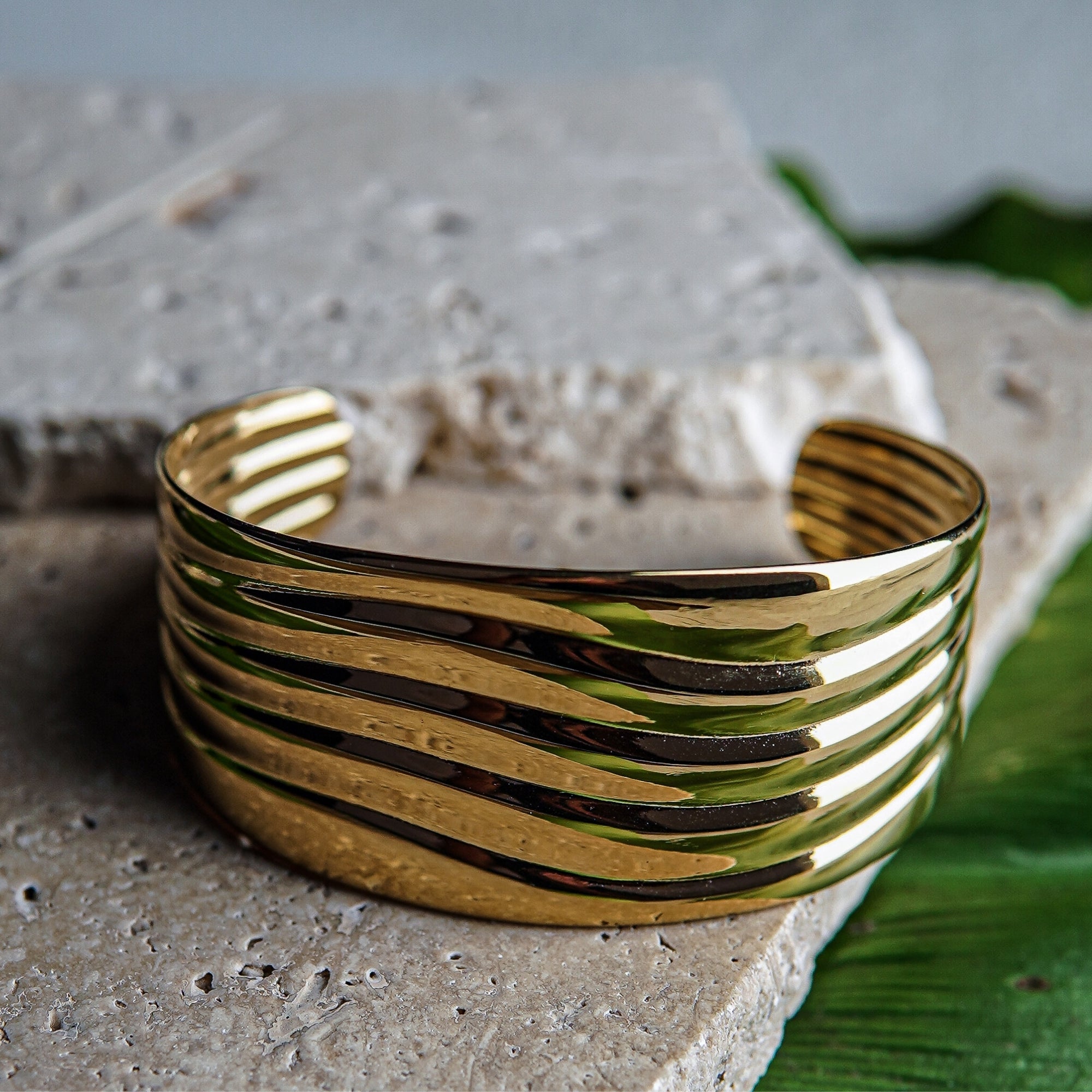 Gold bracelet on a textured surface with a blurred background
