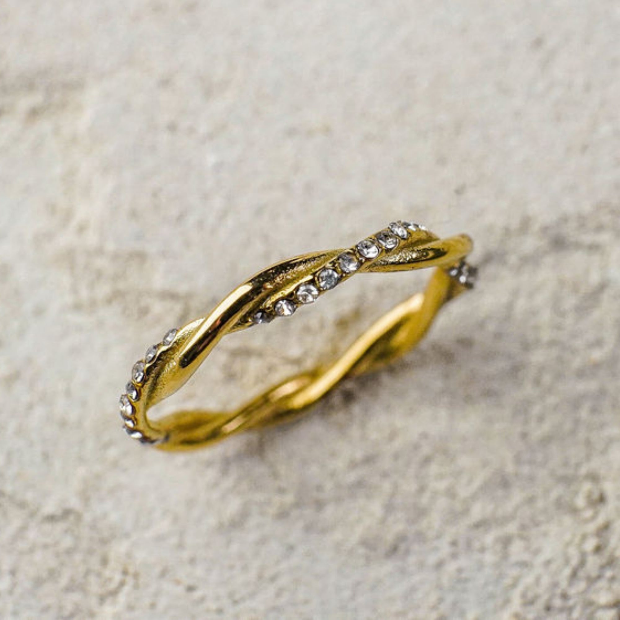Gold bracelet with crystal accents on a textured beige background