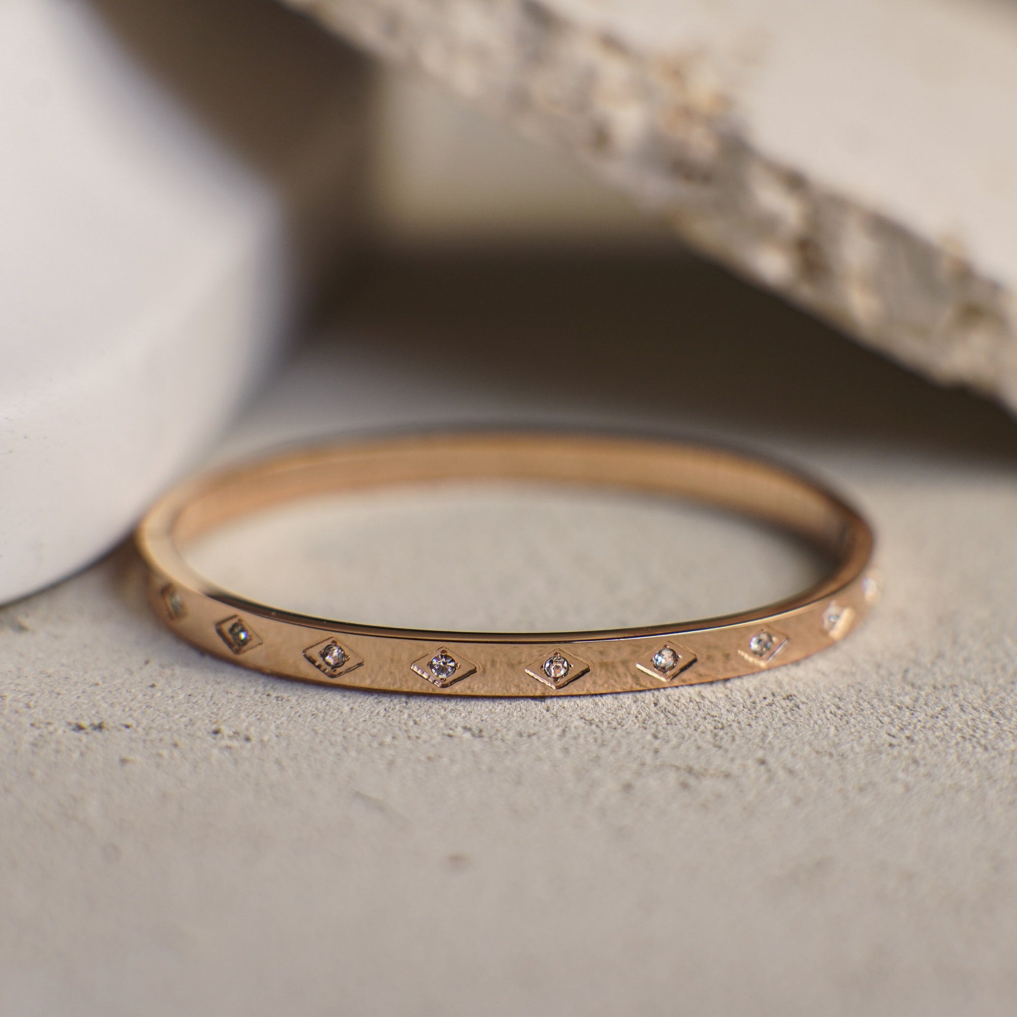 Rose gold bracelet with small diamonds on a textured surface
