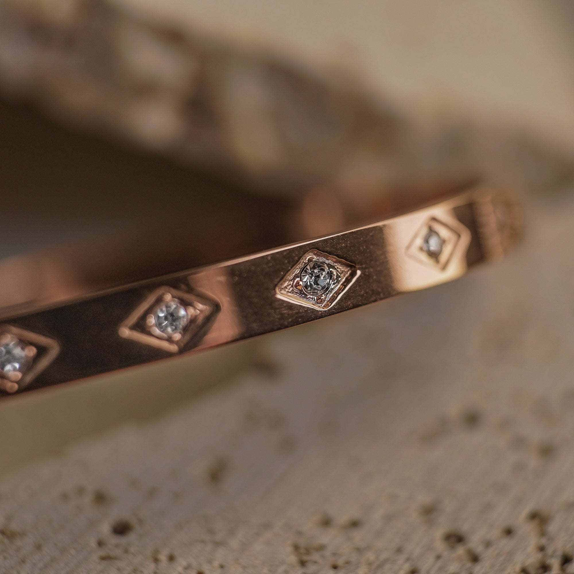 Rose gold ring with diamond accents on a textured surface