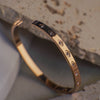 Gold bracelet with embedded stones on a textured surface