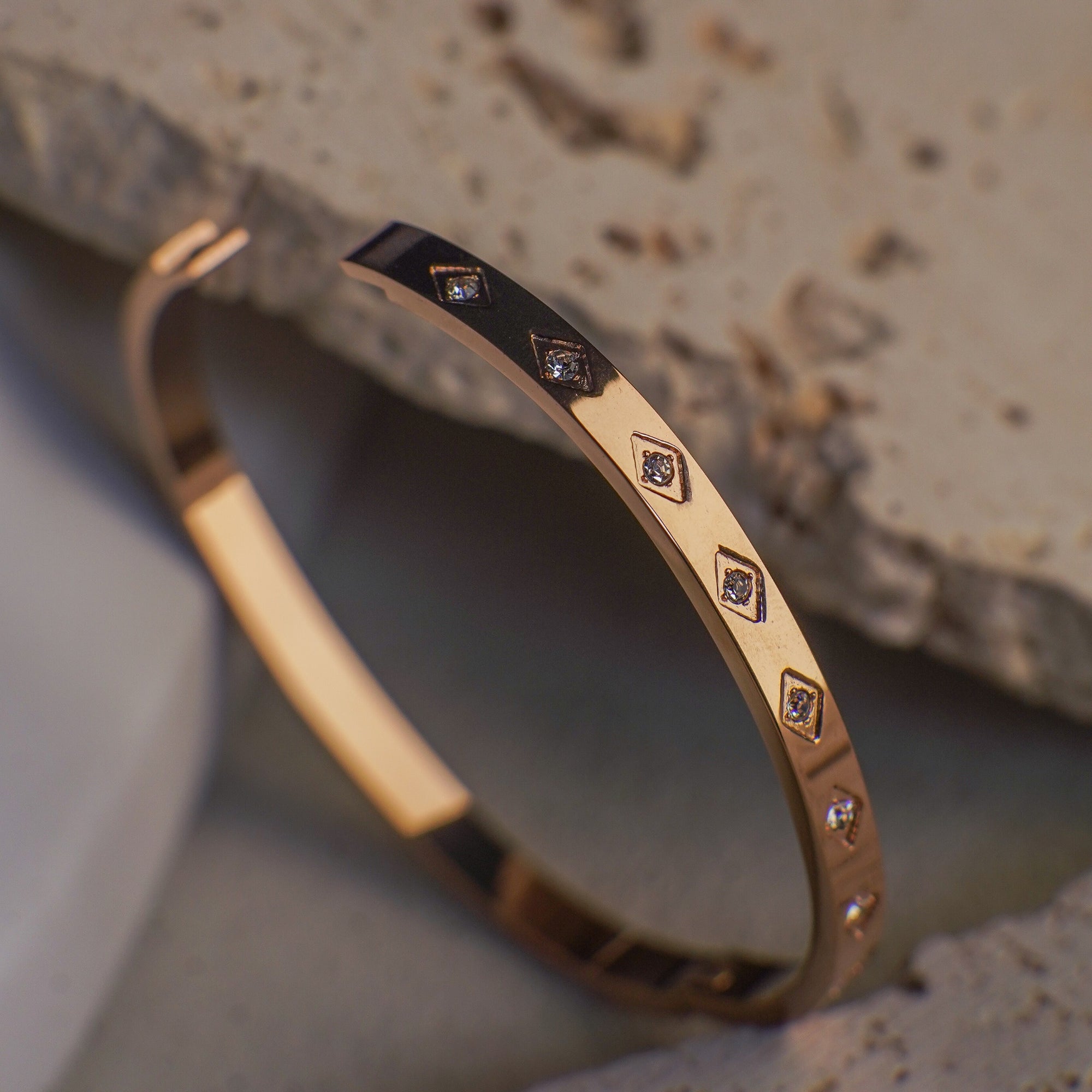 Gold bracelet with embedded stones on a textured surface