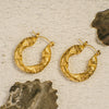Gold hoop earrings on a textured beige background