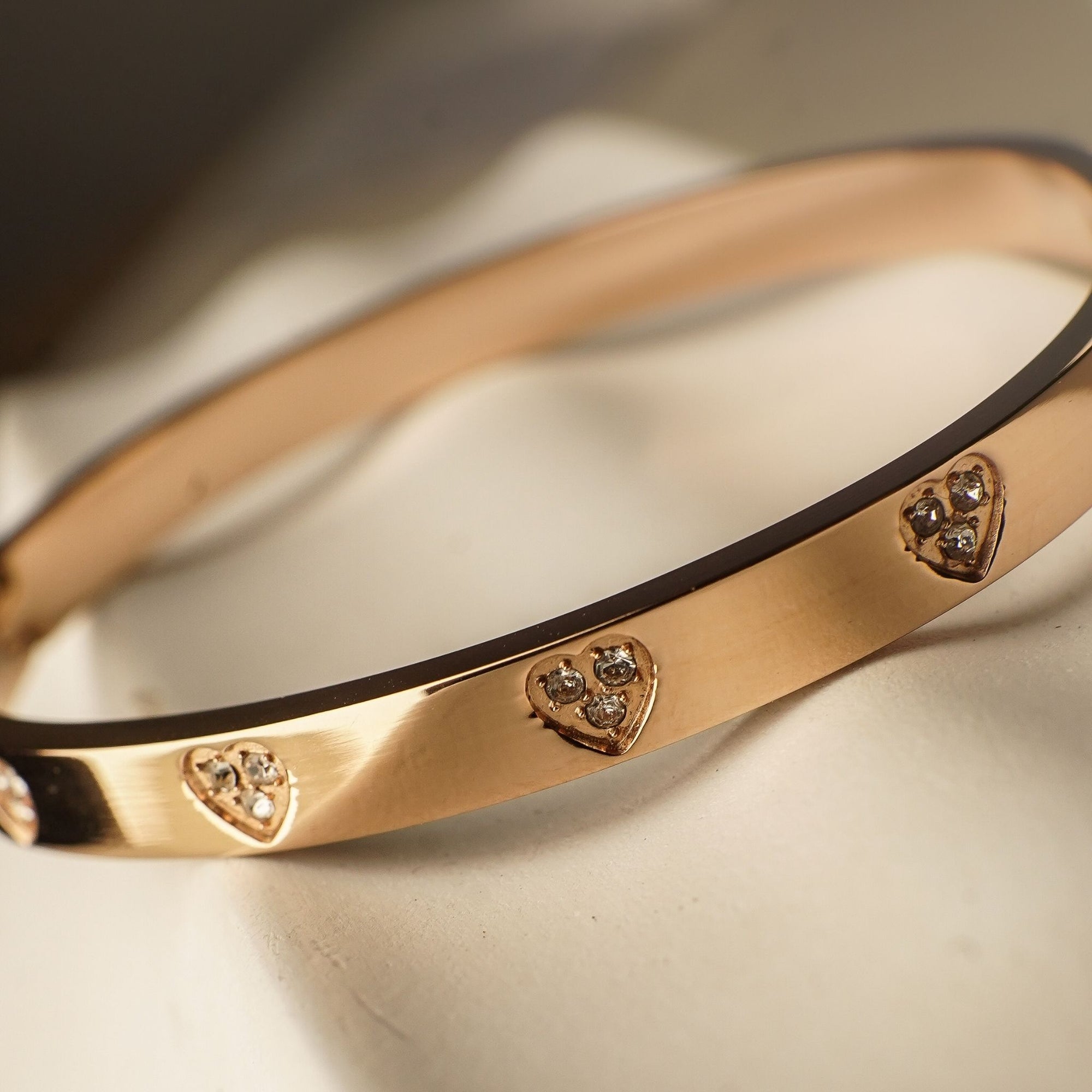 Gold bracelet with heart-shaped diamond accents on a soft fabric background
