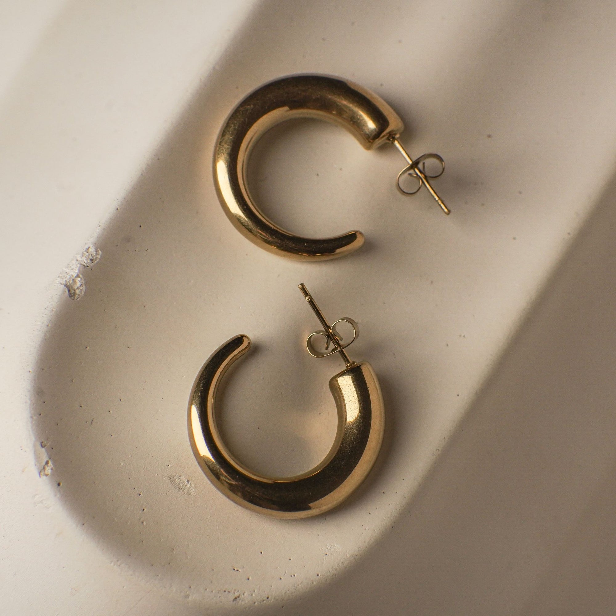 Gold hoop earrings on a textured beige surface