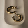 Gold hoop earrings on a light gray surface