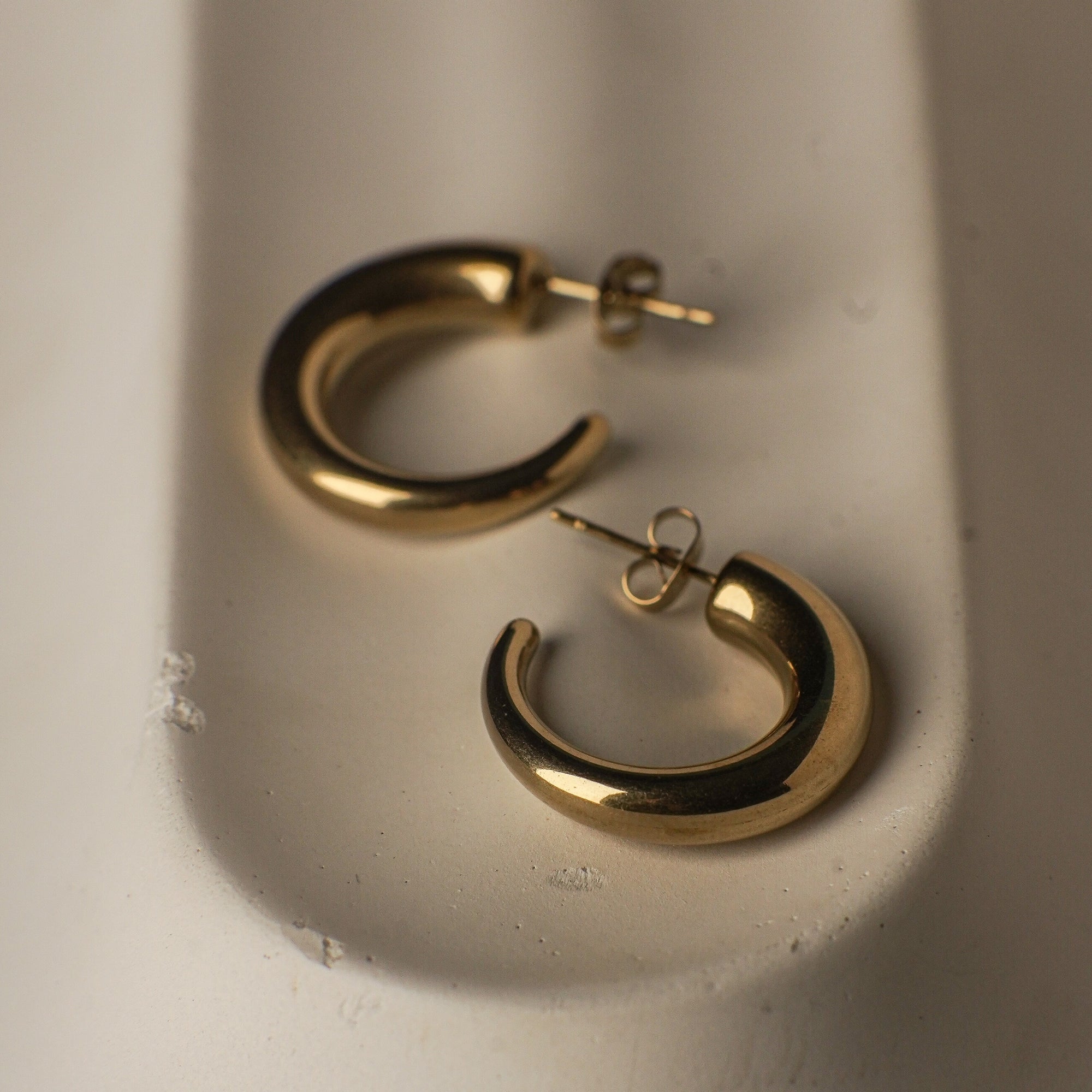 Gold hoop earrings on a light gray surface
