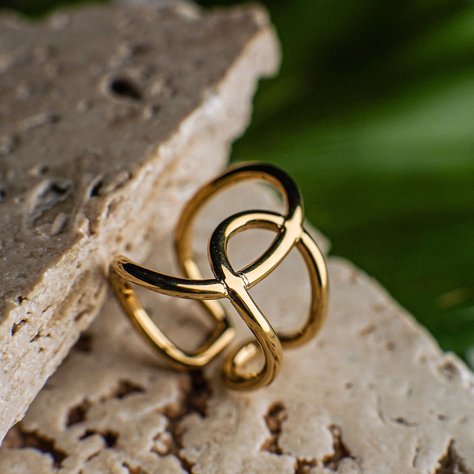 Gold ring on a textured stone surface with a blurred green background