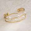 Gold bracelet with pearls on a light beige background