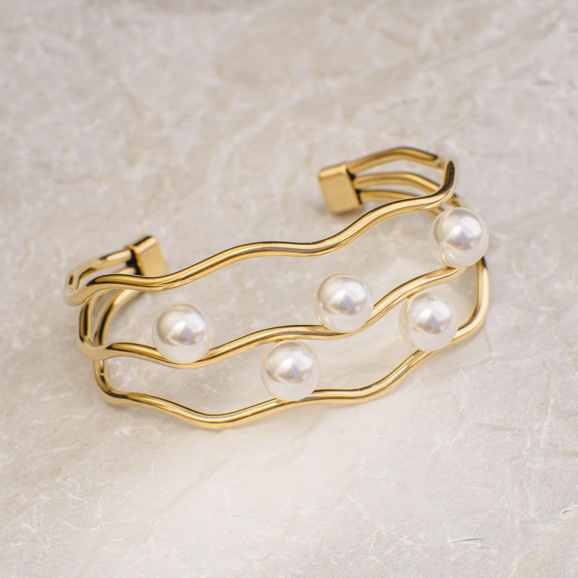 Gold bracelet with pearls on a light beige background