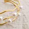 Gold bracelet with pearls on a textured beige surface
