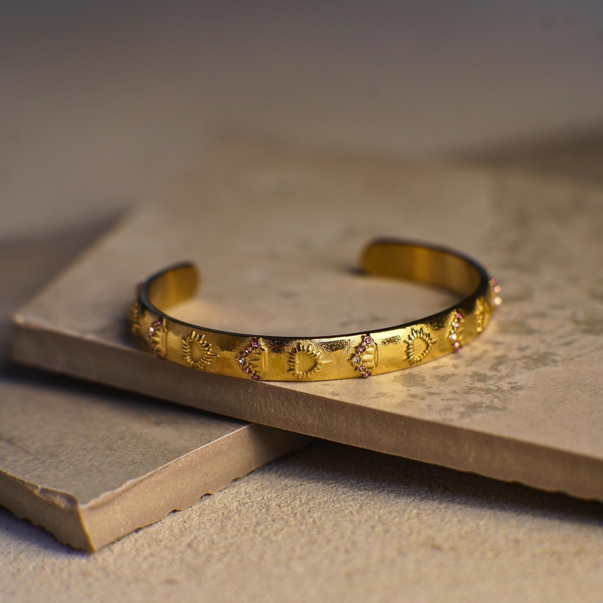 Gold bracelet with intricate designs on a textured surface