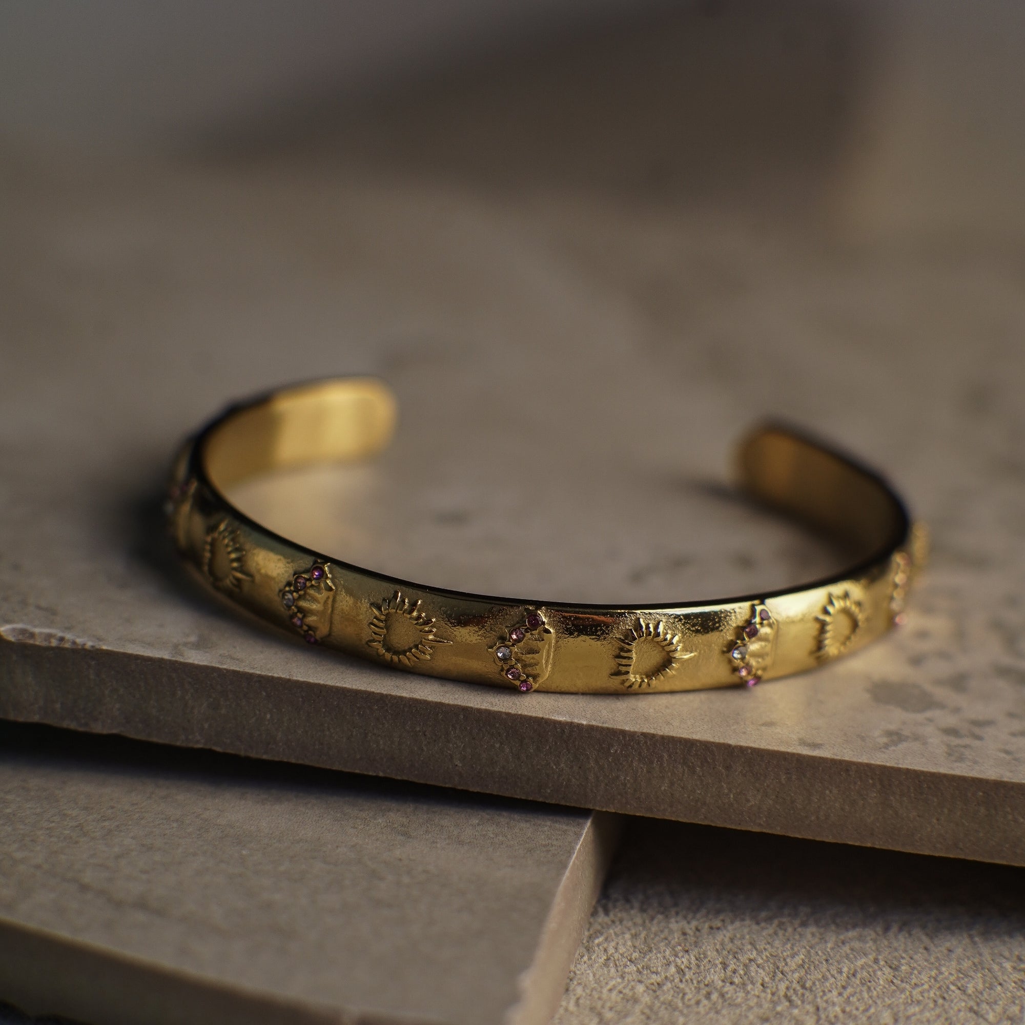 Gold bracelet with embossed design on a stone surface