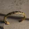 Gold bracelet with intricate designs on a textured surface