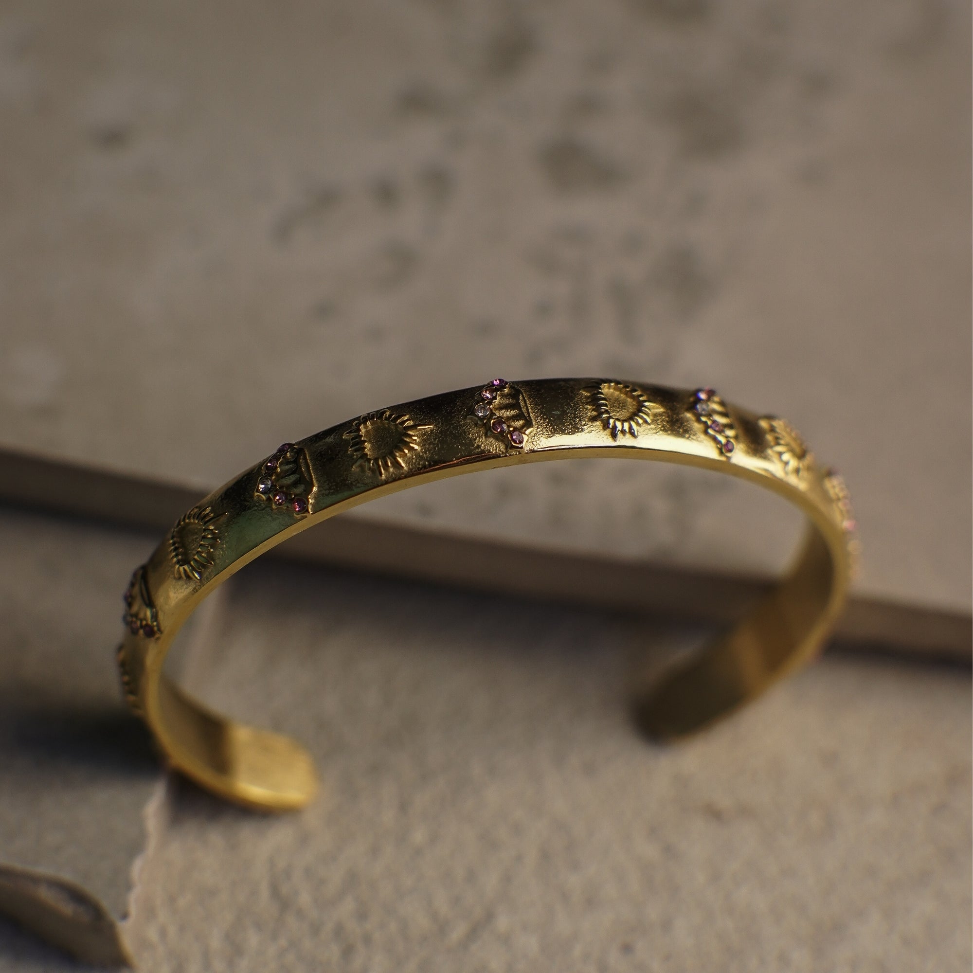 Gold bracelet with intricate designs on a textured surface