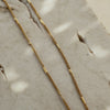 A gold-colored necklace laid out on a textured surface.