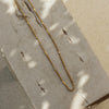 A gold chain necklace on a textured surface