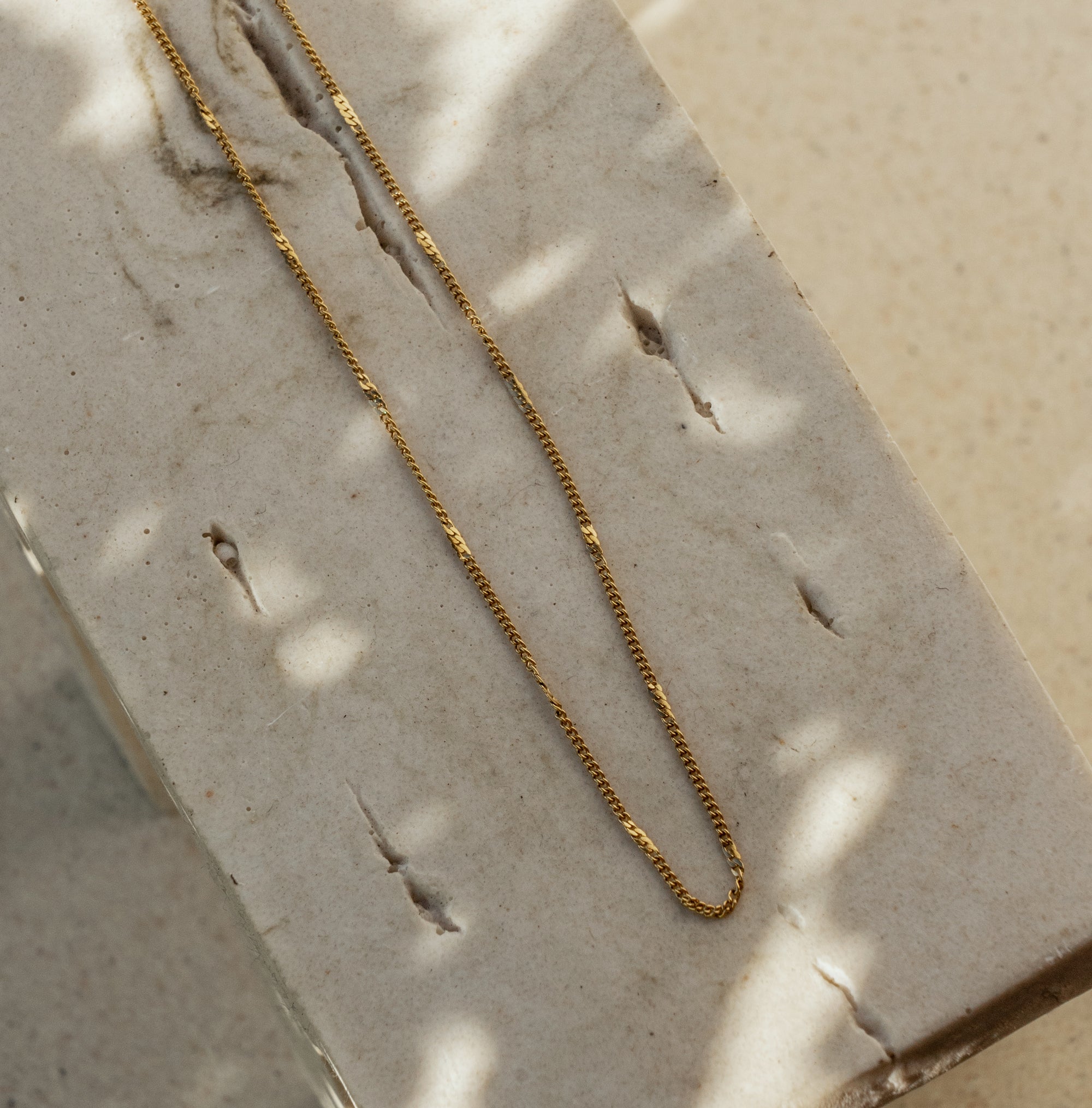 A gold chain necklace on a textured surface