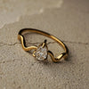 Gold ring with a diamond on a textured beige surface