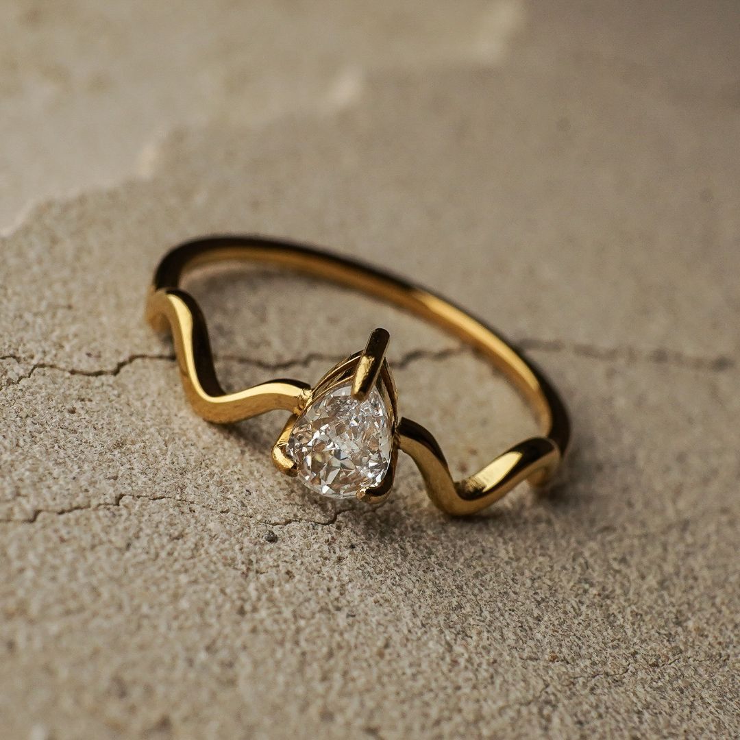Gold ring with a diamond on a textured beige surface