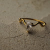 Gold ring with a diamond on a textured beige surface