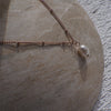 Necklace with a pearl pendant on a stone surface