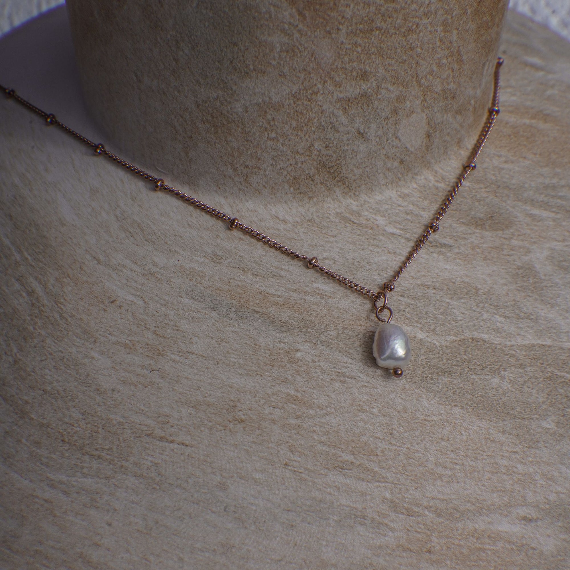 Necklace with a pearl pendant on a textured surface