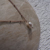 Necklace with a pearl pendant on a stone surface
