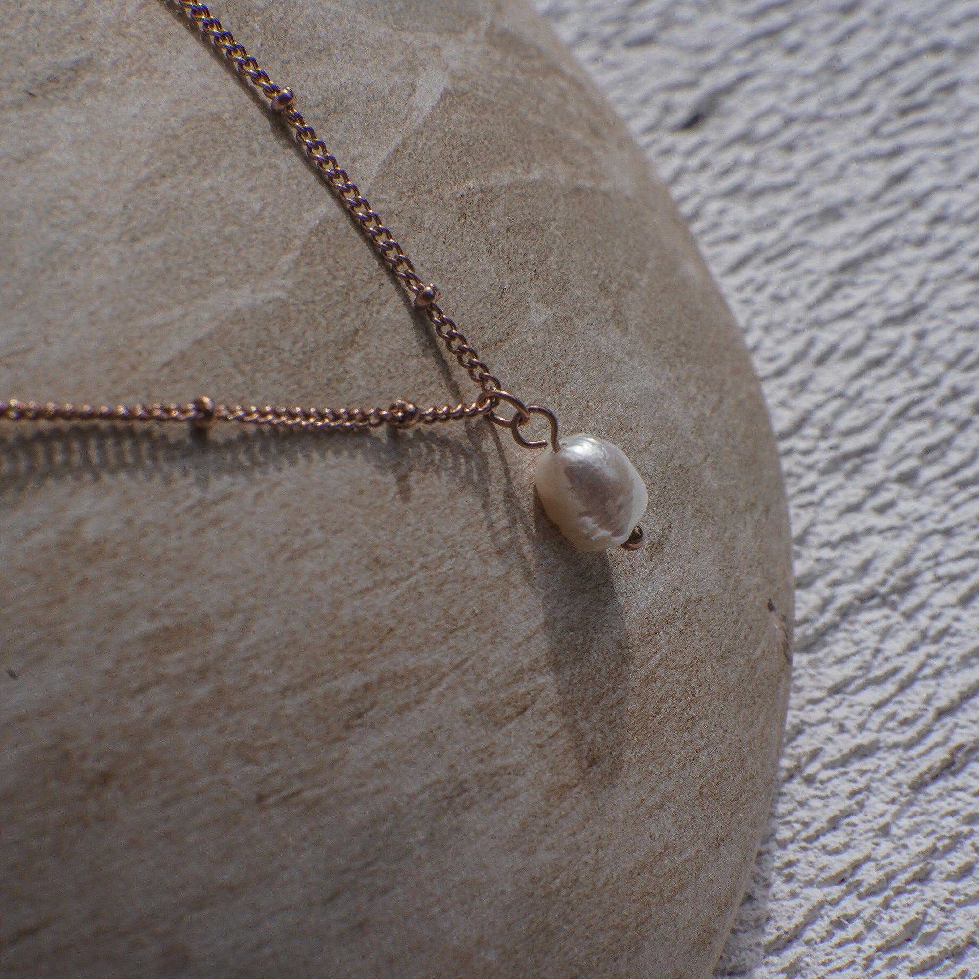 Necklace with a pearl pendant on a stone surface