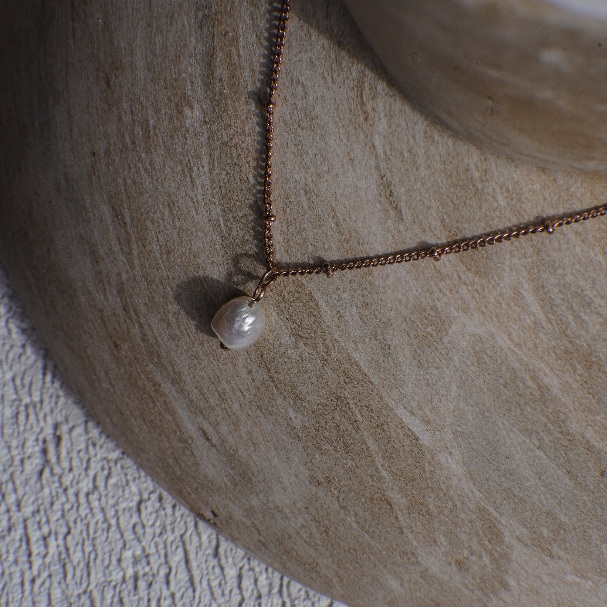 Necklace with a pearl pendant on a textured stone surface